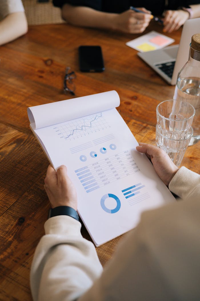 Close-up of hands holding a document with graphs and charts during a business meeting.